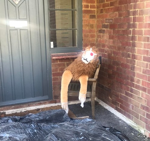 Lion toy in chair wearing face mask.