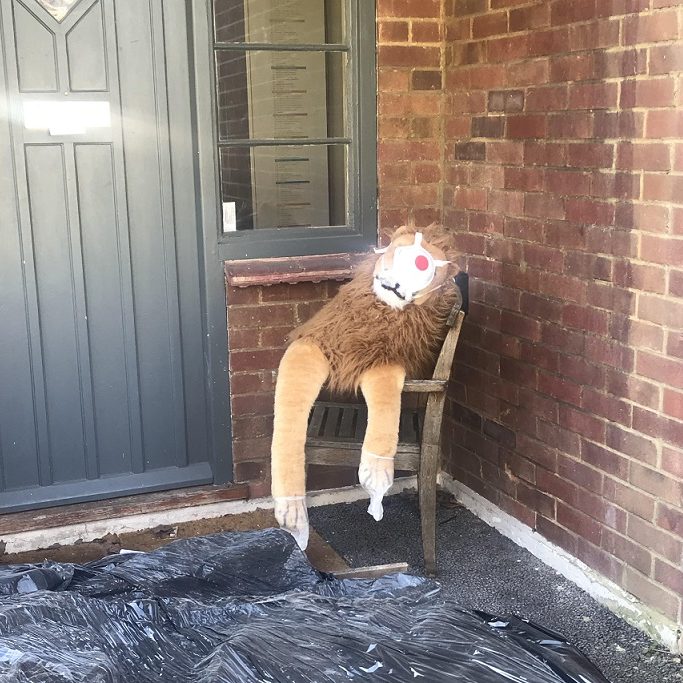 Lion toy in chair wearing face mask.